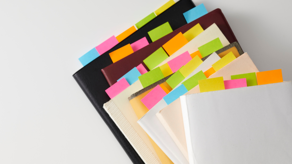 Muistivihkoja joiden sivuja merkitty eri värisin post-it lapuin